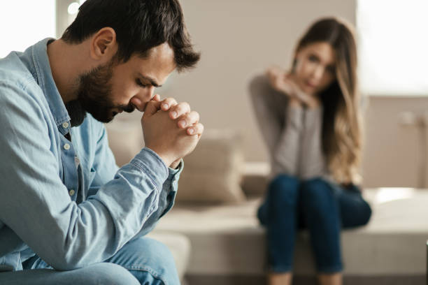 Young man feeling sad after arguing with his girlfriend on sofa at home.