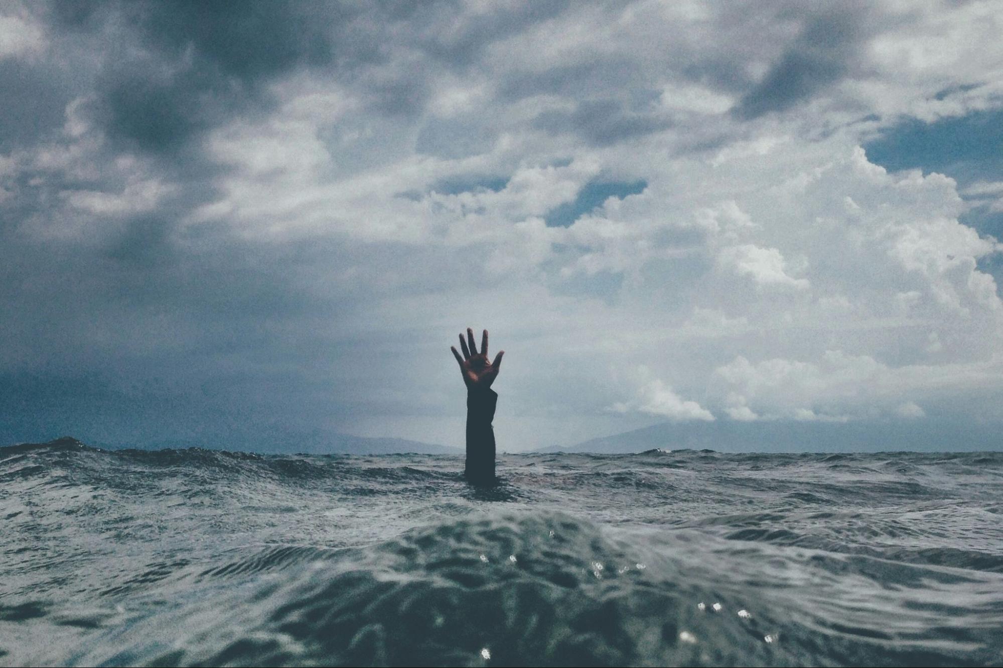 Hand extending out of ocean, reaching for help. 
