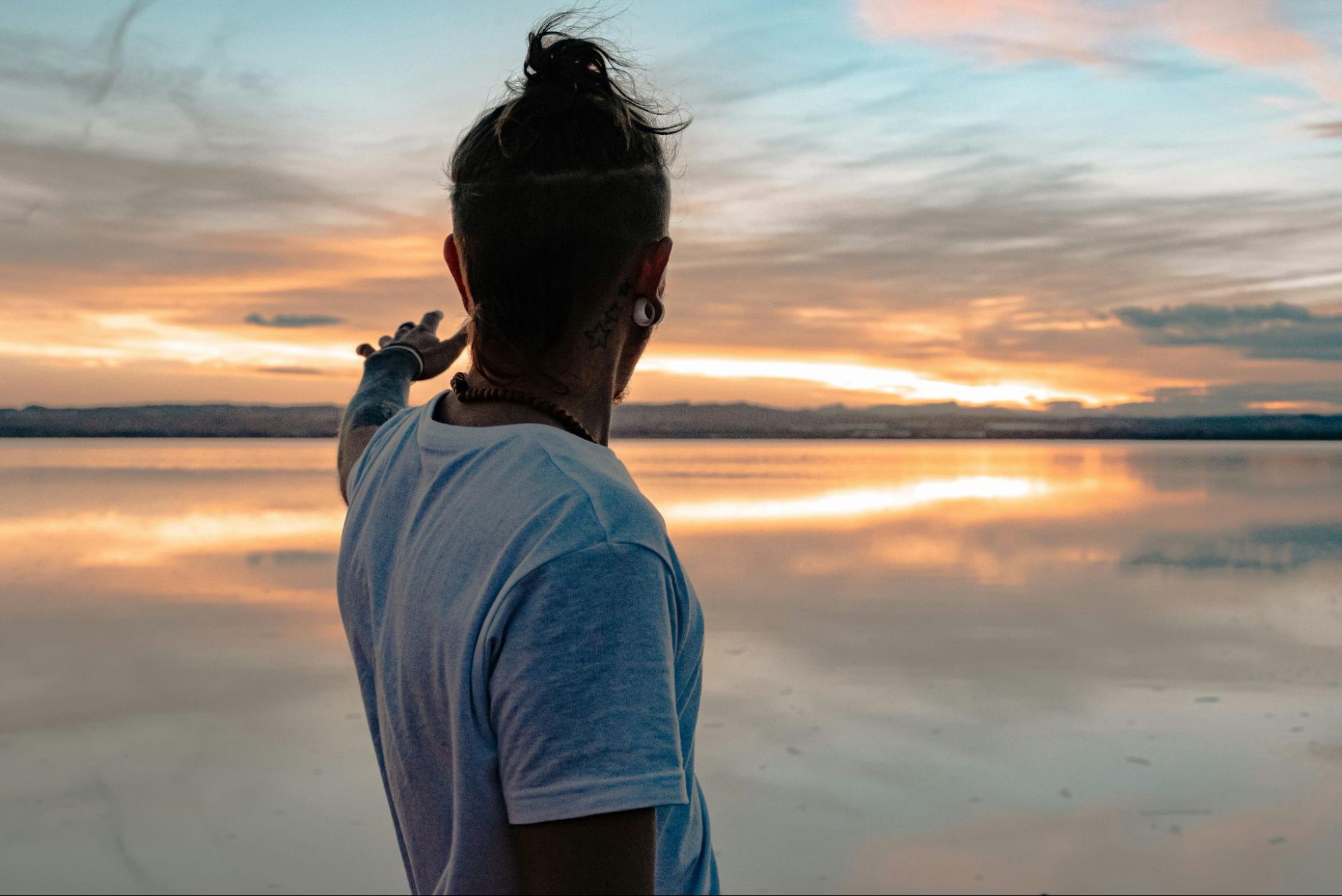 Man in white t-shirt reaching out to the promising horizon.
