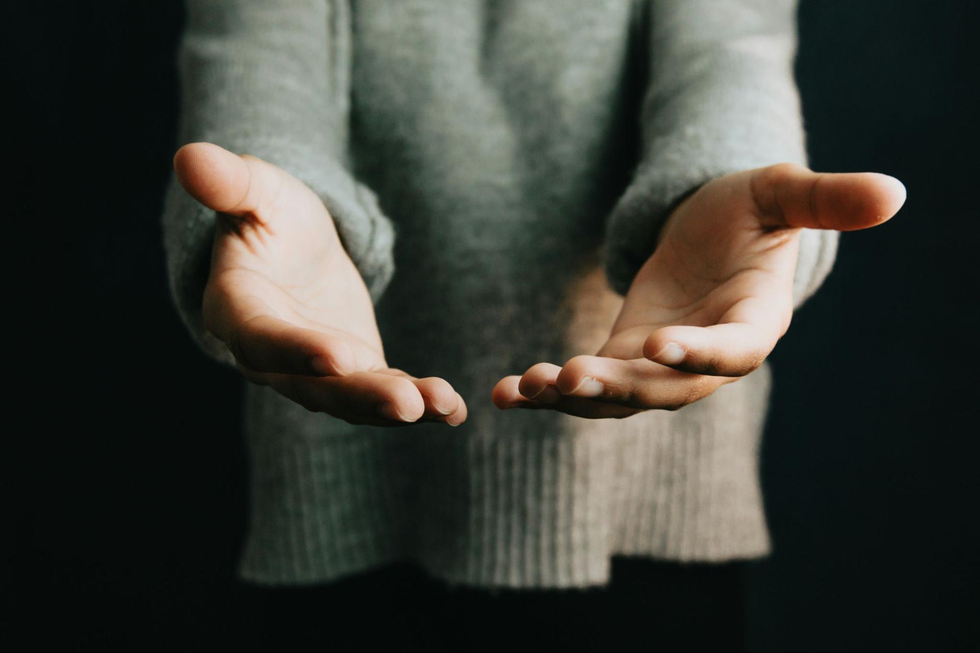 Man standing with outstretched hands offering help.