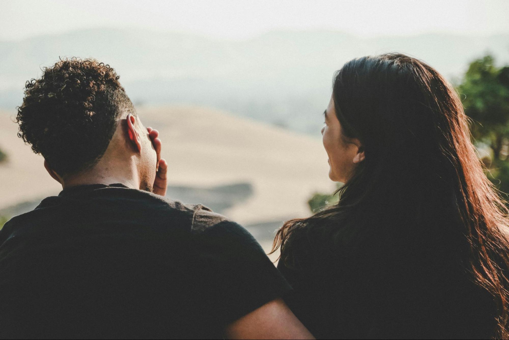 Man and woman sitting together and talking pictured from the back.