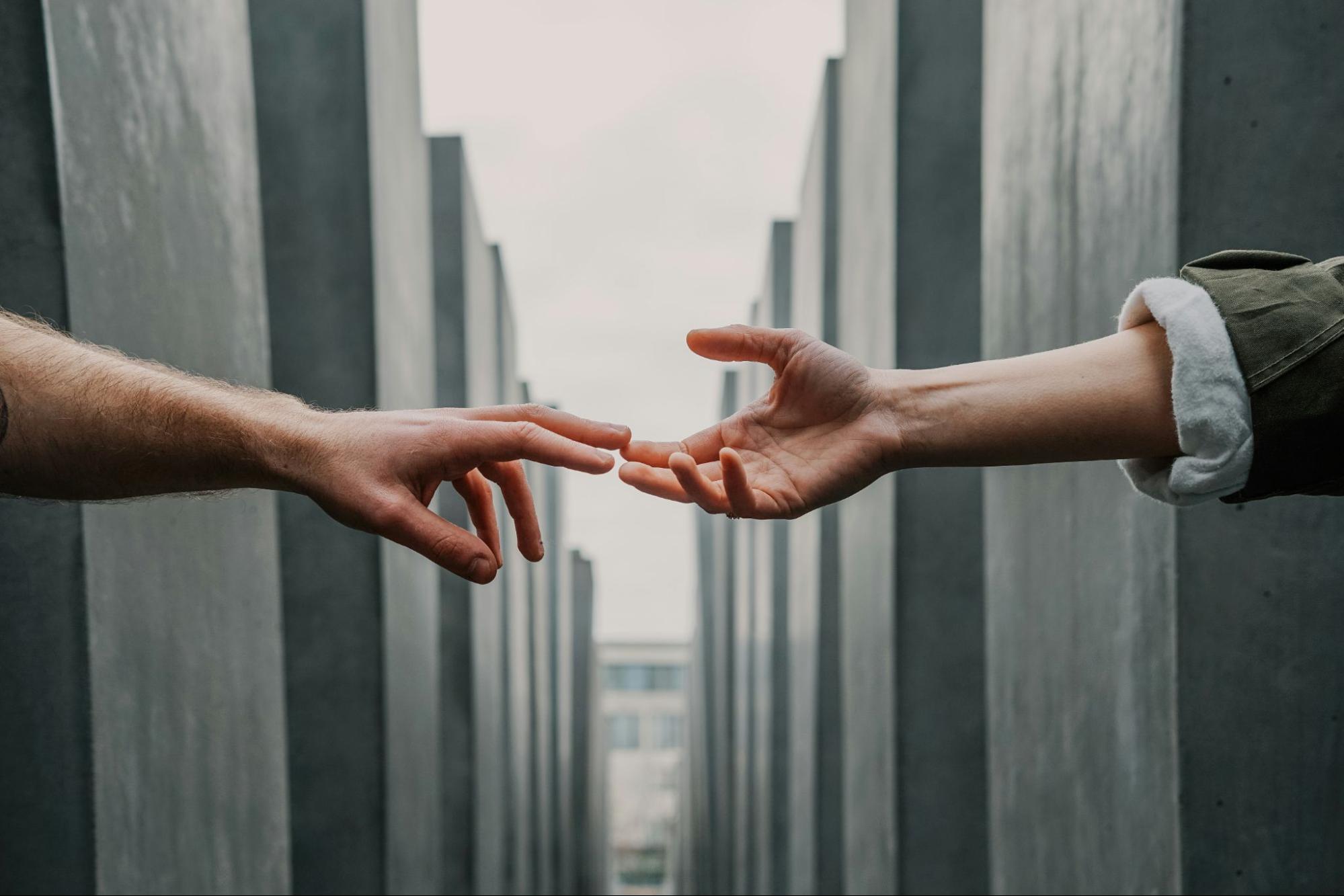 One hand reaching out to another to help in a maze. 