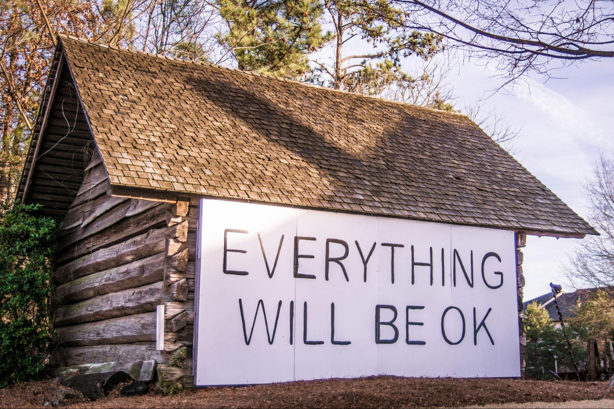 House in the country with a big sign on it's side that says "everything will be ok" 